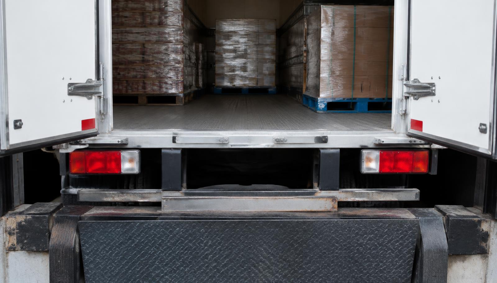 Close-up of an open box truck backed against a loading dock with pallets inside